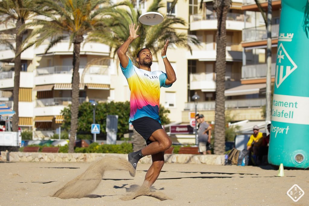 Player leaping to catch a disc on the beach